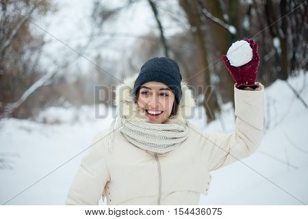 winter girl throwing snowball at camera smiling happy having fun outdoors on snowing winter day playing in snow. Cute playful multicultural Asian Caucasian young woman outdoor enjoying first snow.