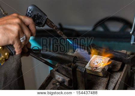 Melting Silver Grains to liquid state in crucible with blowtorch; Goldsmith Workshop; Close-up