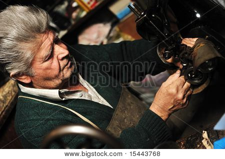 Uomo anziano lavorando con vecchia macchina nella sua officina