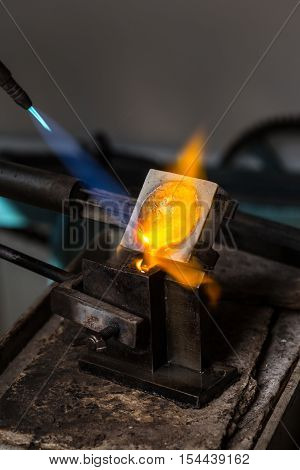 Close-up of Silver Casting from Crucible to Metal Mold with blowtorch; Goldsmith Workshop;