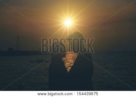 Silhouettes of hugging couple against the sea at sunset. Vintage tone