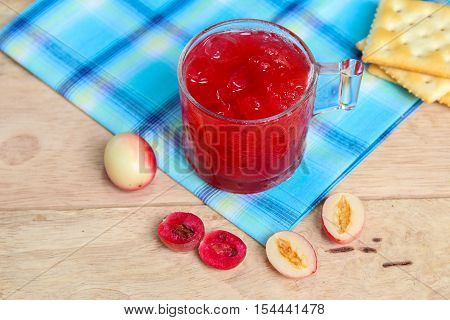 Carandas-plum  juice  in a glass on wooden background