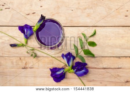 Butterfly pea juice in glass on wooden table with flower.