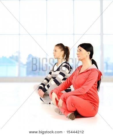 Two girls doing yoga and fitness bautiful bright surround