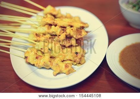 Grilled pork served with peanut sauce or sweet and sour sauce (pork satay); Filtered image processed vintage effect.