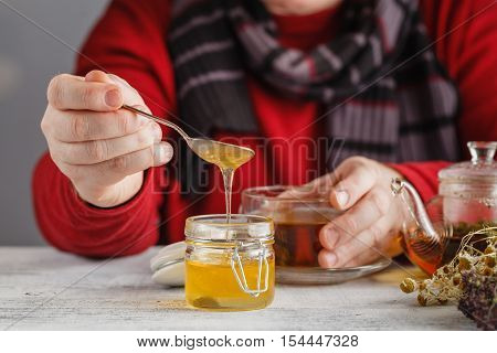 Man Hold Cup Of Hot Tea In Glass Cup, Jar Of Honey, Honey Dipper On The Old Wooden Background