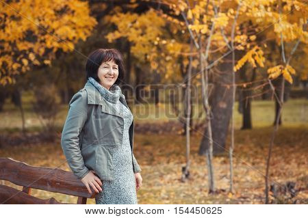 Mature woman is walking in the pak and smilling