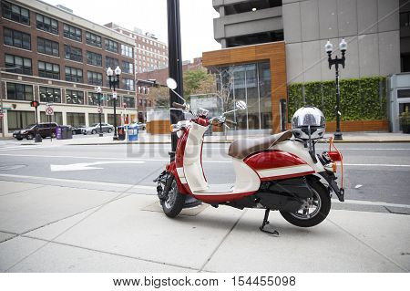 red scooter parked on the sidewalk. scooter and helmet on the street in downtown Boston