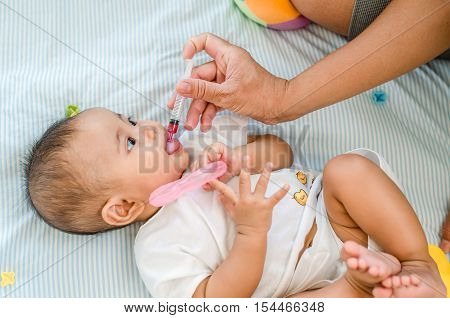 Asian baby girl feeding with liquid medicine