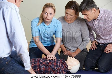 Woman Demonstrating CPR On Training Dummy In First Aid Class