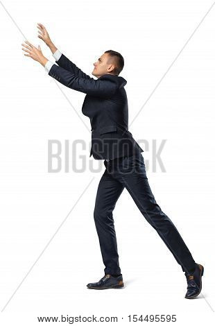 A businessman in profile with his leg set back and his hands up in a catching pose, isolated on the white background. Business and management. Successful people. Poses and gestures.