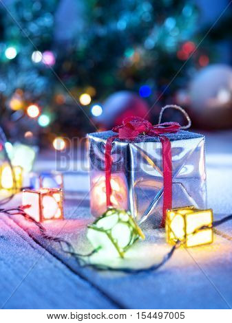 close up view  of lights and gift box on snowbound  wooden back