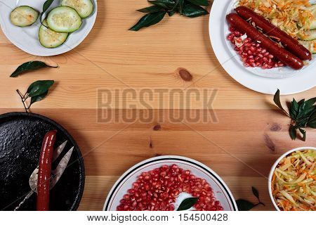 Delicious sausages with vegetables on a wooden light background