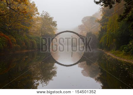 Rakotzbruecke (Devil's bridge) in early morning mist, in autumn, Kromlau, Germany