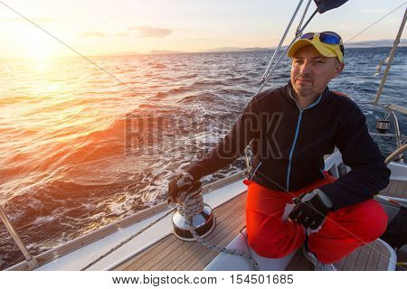 A man sits on his sailing yacht during sunset. Luxery boats. 
