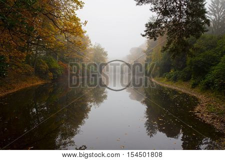 Rakotzbruecke (Devil's bridge) in early morning mist, in autumn, Kromlau, Germany