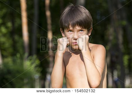 portrait of a boy in nature which shows his muscles