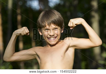 portrait of a boy in nature which shows his muscles