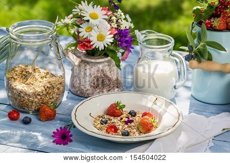 Breakfast with oatmeal fruit and milk on old wooden table