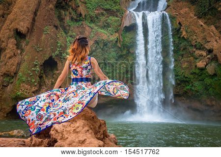 Beautiful waterfall in Morocco. Back woman beautiful dress looking fall Ouzoud Grand Atlas. Exotic nature North Africa
