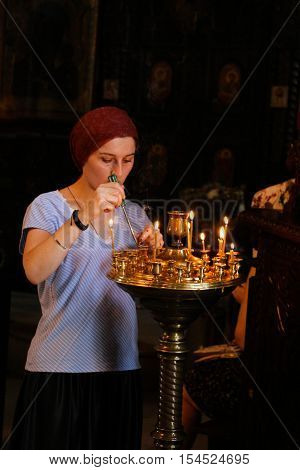 Woman brning candles in Church in Georgia