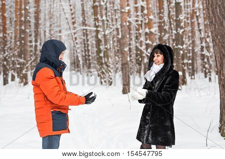 Snowball fight. Winter couple having fun playing in snow outdoors