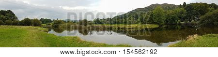 Wide Panoramic view of pond and beautiful reflections in Ambleside countryside Cumbria UK