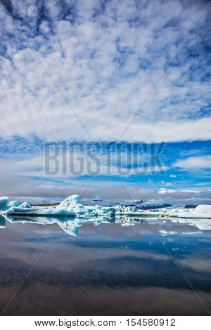 Iceland. Ice magnificence. Floating ice and clouds are reflected in smooth mirror water of the Ice lagoon