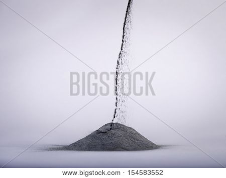 Pouring lead powder over gray background.