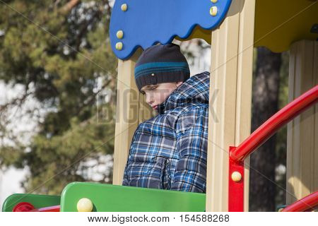 In the spring of the playground is a sad hurt little boy.