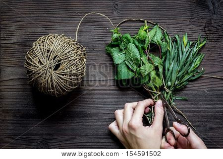 mint and estragon on wooden background with hands top view.
