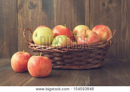 Apples in basket on wooden rustic background. Autumn and harvest concept selective focus toned horizontal