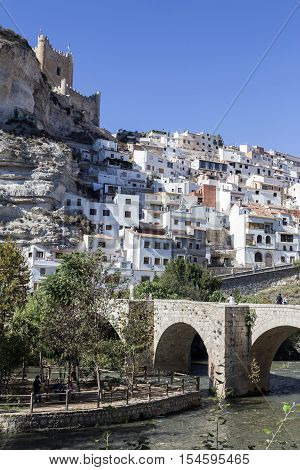 Alcala del Jucar Spain - October 29 2016: Roman bridge located in the central part of the town to its passage by the river Jucar at the top of mountain limestone is situated castle of Almohad origin of the century XII take in Alcala of the Jucar Albacete