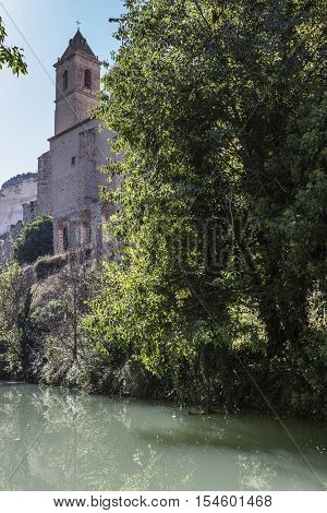 Alcala del Jucar Spain - October 29 2016: Passage along the river Jucar right the church of San Andres styles late Gothic and Neoclassic take in Alcala of the Jucar Albacete province Spain