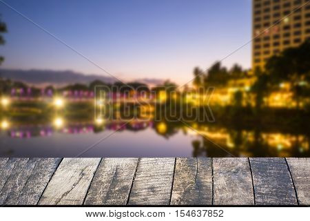 Empty of wood desk form and bokeh light of night city scape background for product presentation display montage.