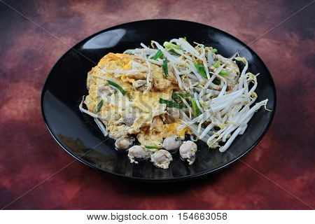 Thai food.,Fried egg and oyster with bean sprouts and shallot as Hoi Tod Khai in Thai served with chili sauce.