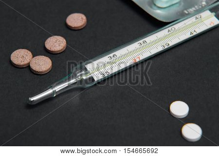 Bunch of blue pills with thermometer and gauze on the white background