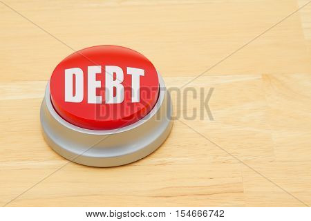 A Debt red push button A red and silver push button on a wooden desk with text Debt