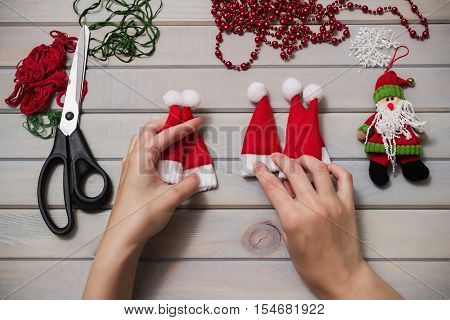 Christmas tree toys handmade. Wooden background. Top view. Making New Year decoration. Christmas ornaments. Little Santa Claus hats.