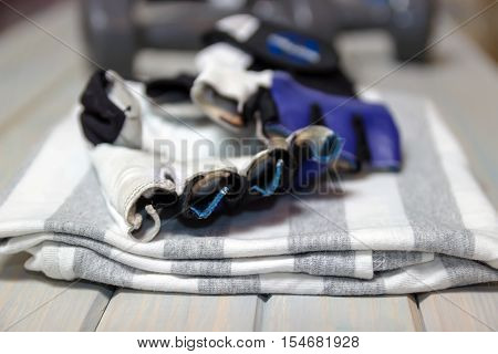 Fitness clothing. Shirt, gloves on a wooden light background. Items for the sport. Sports equipment.