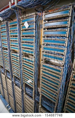 Color image of an old telephone exchange wit many wires.