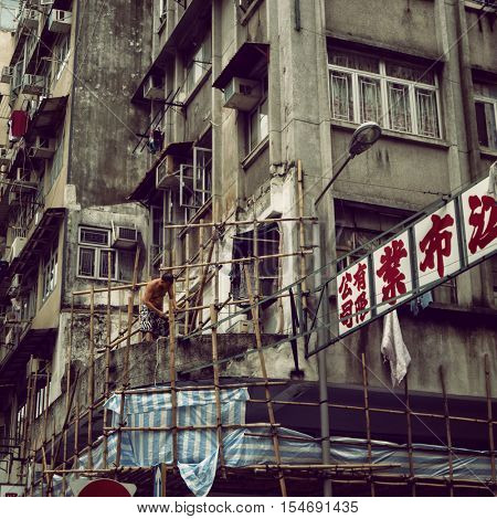 Hong Kong - October 2016: Kowloon street view with man and bamboo scaffolding. Retro look.