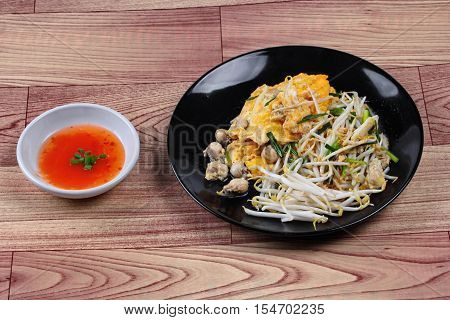 Thai food.,Fried egg and oyster with bean sprouts and shallot as Hoi Tod Khai in Thai served with chili sauce.