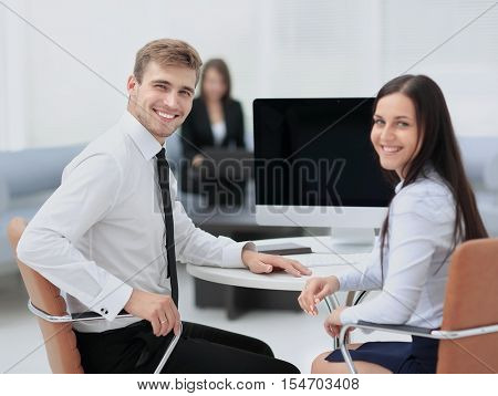 Happy business people looking at camera in office and  using com