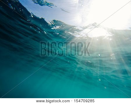 Rays of sun light shining underwater below ripples