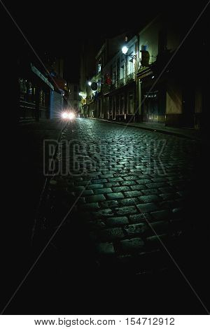 Car lights down empty dark alley at night