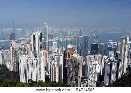Skyline of Hong Kong city and Victoria Harbour. View from Victoria Peak to the bay on afternoon time with sunlight. Beautiful shot of many high skyscrapers covered with smog in Hong Kong China Asia.