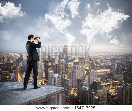 Businessman looks at the city from the roof with binoculars