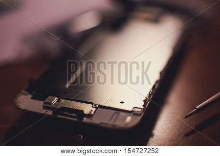 A close-up process of disassemble and dismantle modern mobile phone smartphone with broken shattered display glass and changing details at home