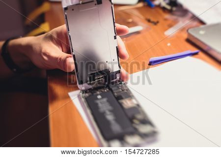 A close-up process of disassemble and dismantle modern mobile phone smartphone with broken shattered display glass and changing details at home